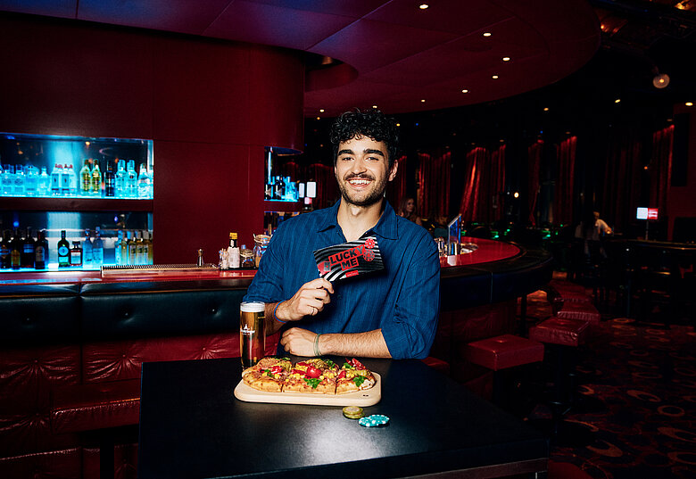Mann an der Casino Bar mit Lucky Me Gutschein, Pinsa und Cola
