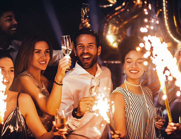 Gruppe von Menschen feiern Silvester mit Sekt und Wunderkerzen