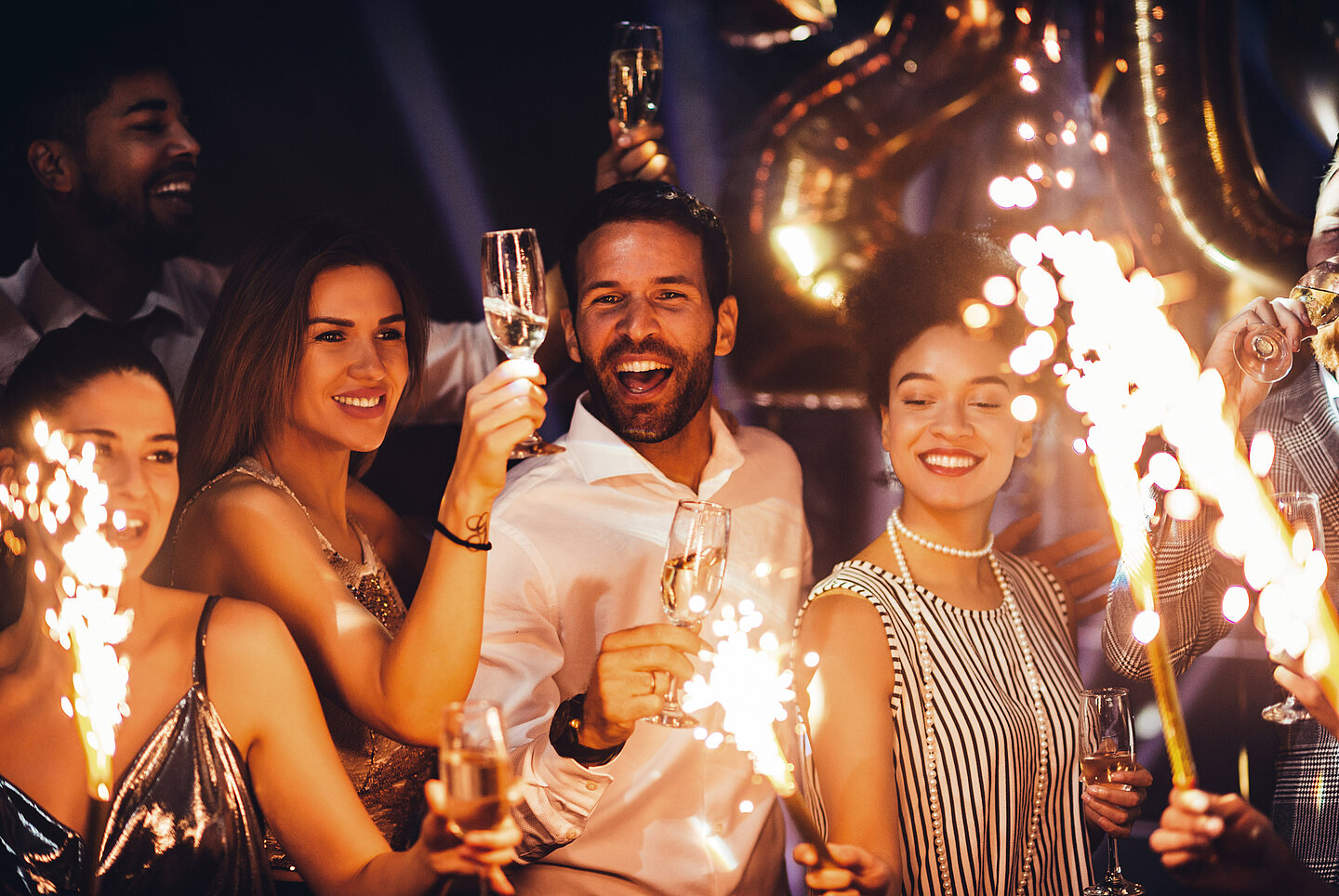Gruppe von Menschen feiern Silvester mit Sekt und Wunderkerzen