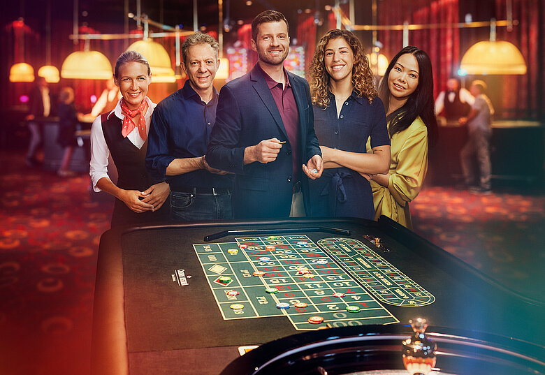Croupière und Gäste-Gruppe stehen vor Roulette-Tisch