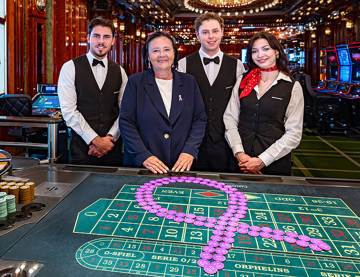 Pink Casino Night - Doris Kiefhaber Geschäftsführerin der Österr. Krebshilfe und der Aktion Pink Ribbon mit Croupière und Croupiers am Roulette-Tisch mit Pink Ribbon Symbol