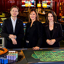 Drei Key Account Manager:innen - ein Herr und zwei Damen - im Casino Wien beim Roulette-Tisch