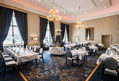 Großer Restaurant Raum im barocken Stil mit dunkelblauen Akzenten, schön gedeckte Tische