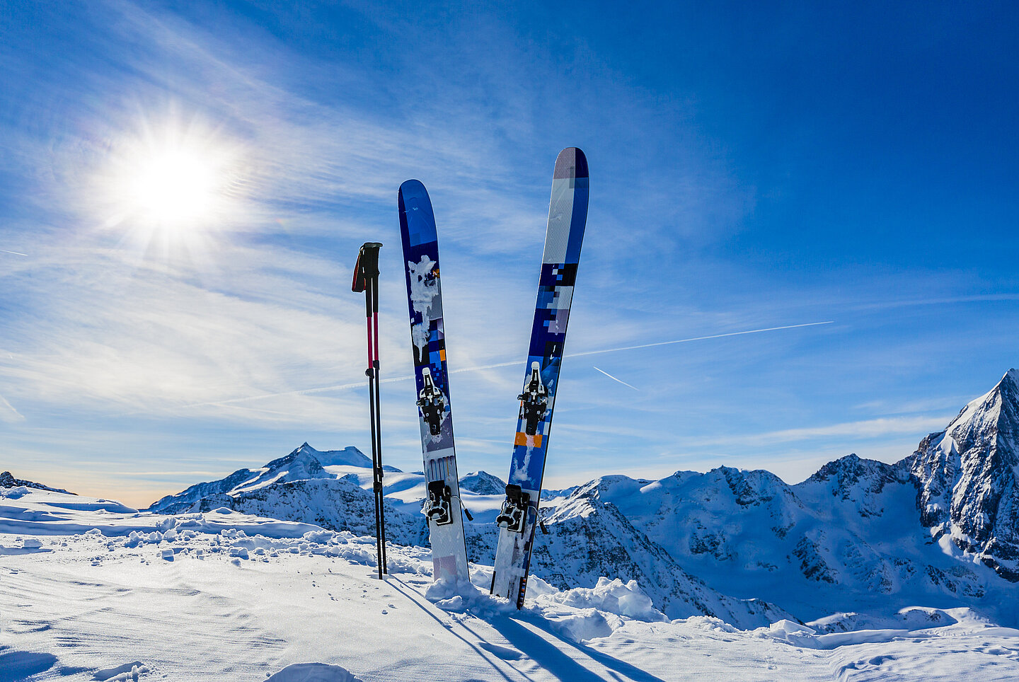 Ein Paar Ski steckt im Schnee auf einer Skipiste